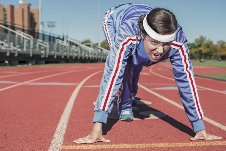 Athlete in starting position on a track, embodying the fusion of motivation and discipline for personal growth