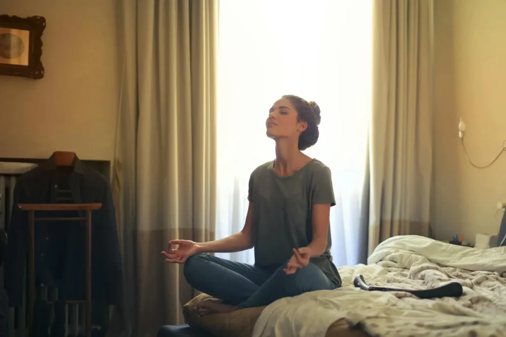 A young professional meditating on a bed, reflecting on personal growth and development goals.